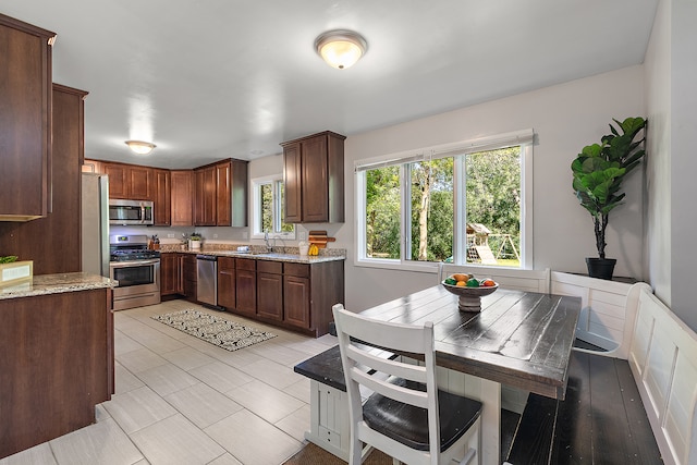 kitchen featuring light stone counters, appliances with stainless steel finishes, and sink