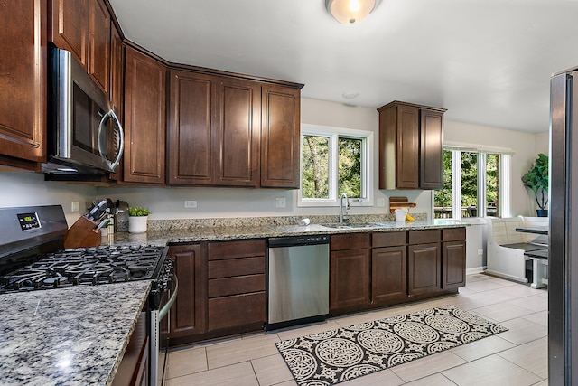 kitchen featuring stainless steel appliances, a wealth of natural light, stone countertops, and sink