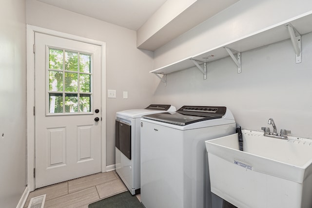 laundry room with hardwood / wood-style floors, separate washer and dryer, and sink