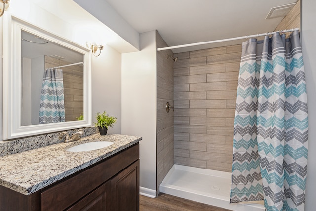 bathroom with vanity, walk in shower, and hardwood / wood-style floors