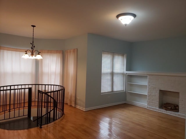 interior space featuring built in features, an inviting chandelier, and wood-type flooring