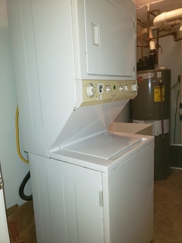 washroom featuring stacked washer and dryer, tile patterned floors, and water heater