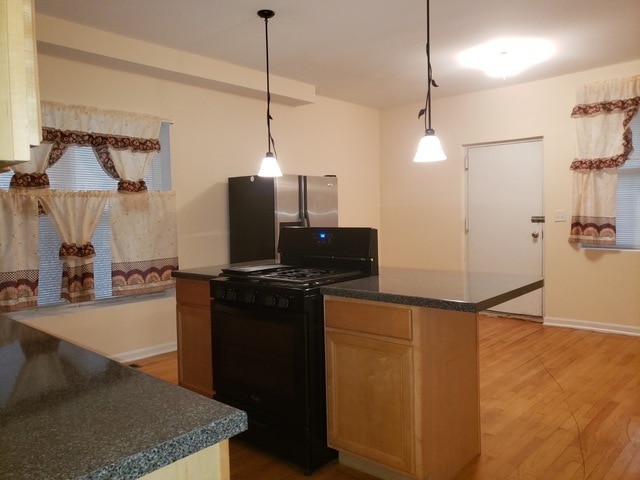 kitchen with pendant lighting, stainless steel refrigerator with ice dispenser, light hardwood / wood-style floors, and black gas stove