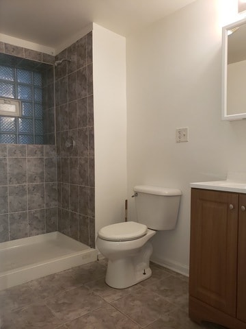 bathroom with vanity, toilet, tile patterned floors, and a tile shower