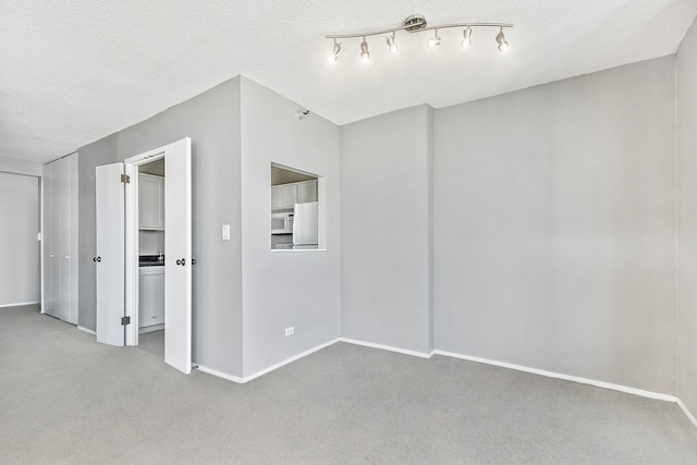 carpeted empty room with a textured ceiling and rail lighting