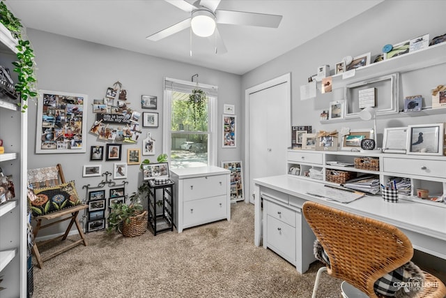 office space featuring built in desk, ceiling fan, and light colored carpet