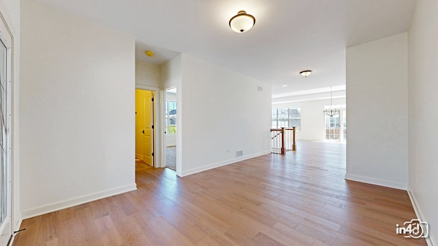 empty room featuring light hardwood / wood-style flooring and a chandelier