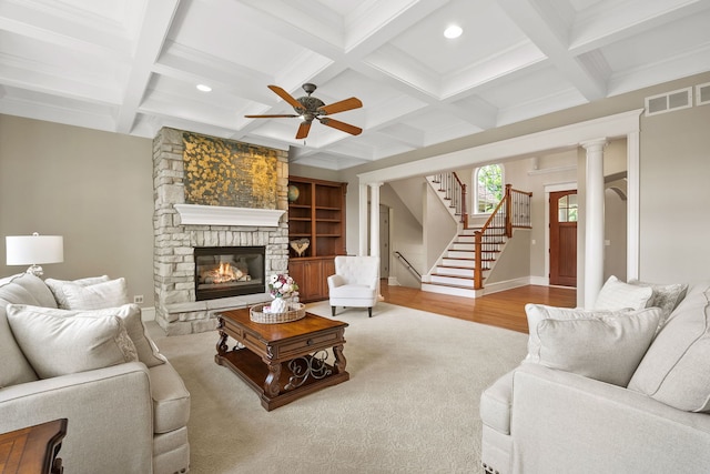 living room with a stone fireplace, decorative columns, coffered ceiling, ceiling fan, and beam ceiling