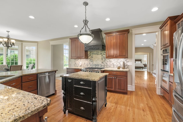 kitchen featuring a kitchen island, backsplash, custom exhaust hood, light stone counters, and stainless steel appliances