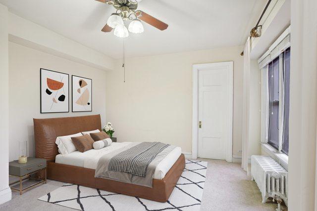 bedroom with radiator, light colored carpet, and ceiling fan