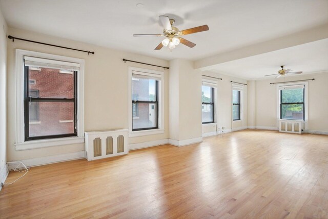 spare room featuring radiator, light hardwood / wood-style flooring, and ceiling fan