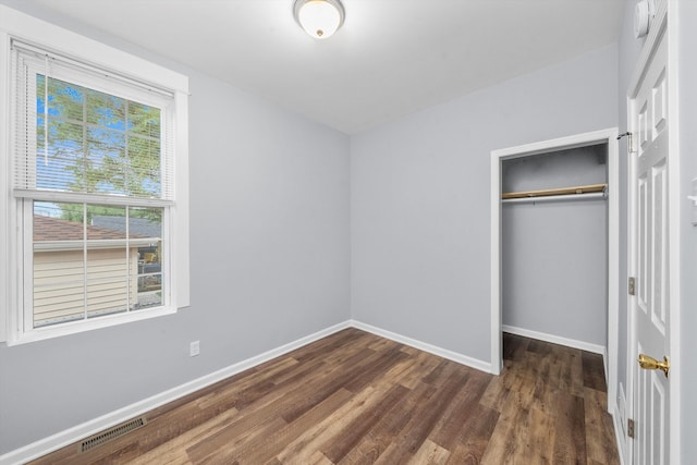 unfurnished bedroom featuring a closet and dark wood-type flooring