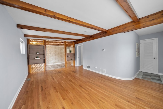 unfurnished living room featuring beam ceiling and light tile patterned floors