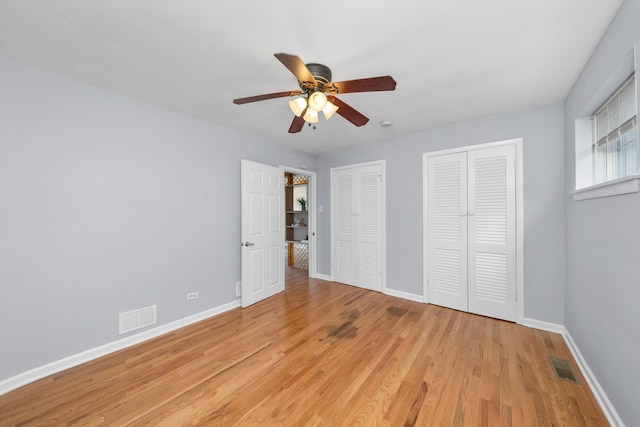 unfurnished bedroom with multiple closets, ceiling fan, and light hardwood / wood-style floors