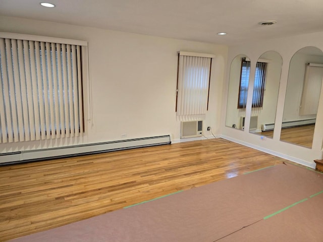 spare room with baseboard heating and wood-type flooring