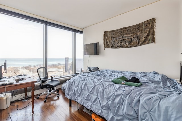 bedroom with a wall of windows, a water view, and dark hardwood / wood-style floors