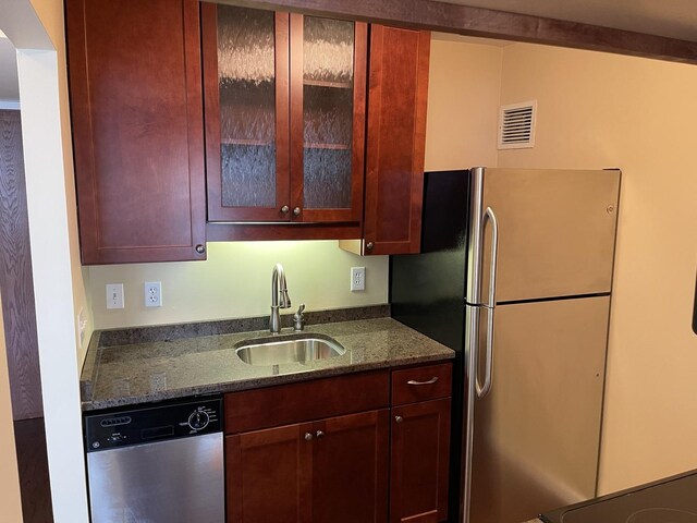 kitchen featuring stainless steel appliances, dark stone countertops, and sink