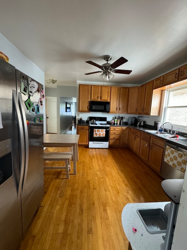 kitchen with appliances with stainless steel finishes, sink, light hardwood / wood-style flooring, and ceiling fan