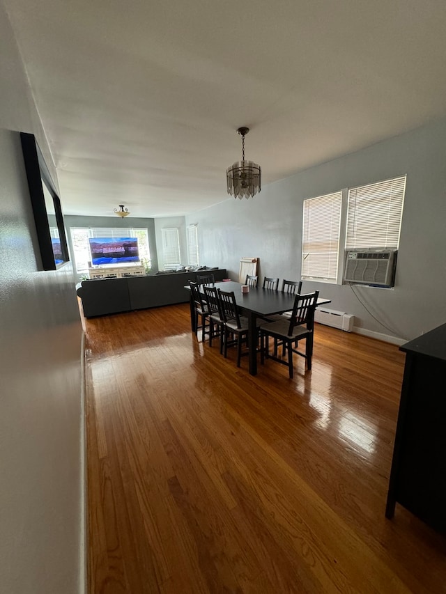 dining room with a notable chandelier, cooling unit, wood-type flooring, and baseboard heating