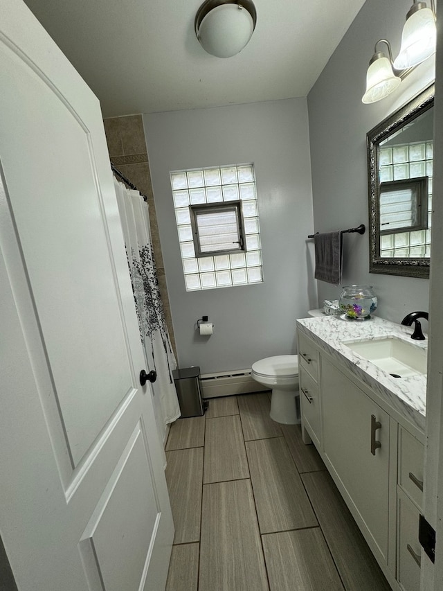 bathroom with toilet, vanity, baseboard heating, and tile patterned flooring