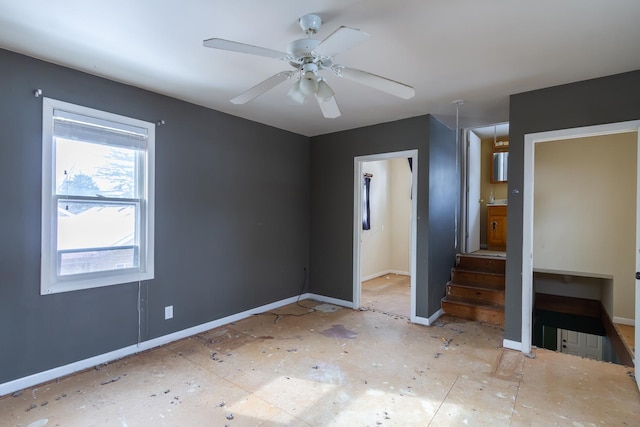 unfurnished room featuring a ceiling fan and baseboards