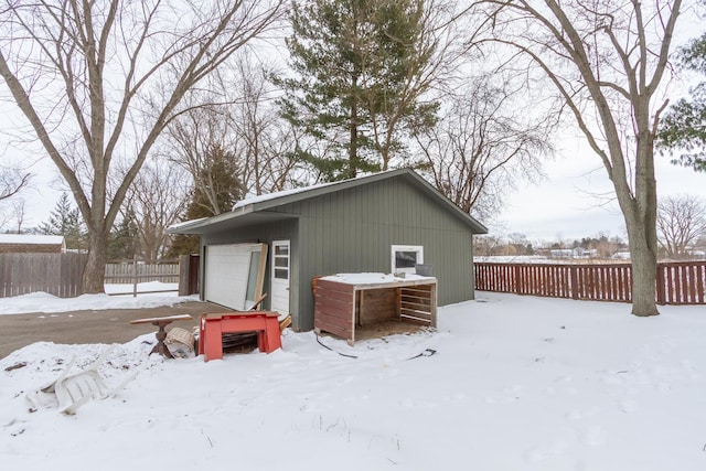 snow covered rear of property featuring a garage and fence