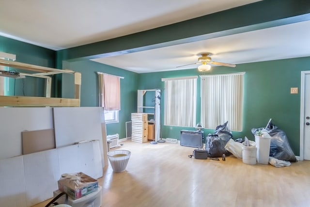 interior space with ceiling fan, beamed ceiling, wood finished floors, and baseboards