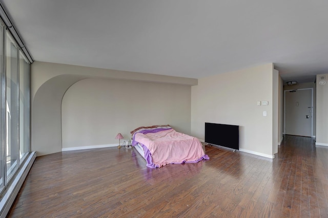 unfurnished bedroom featuring a baseboard heating unit and dark hardwood / wood-style flooring