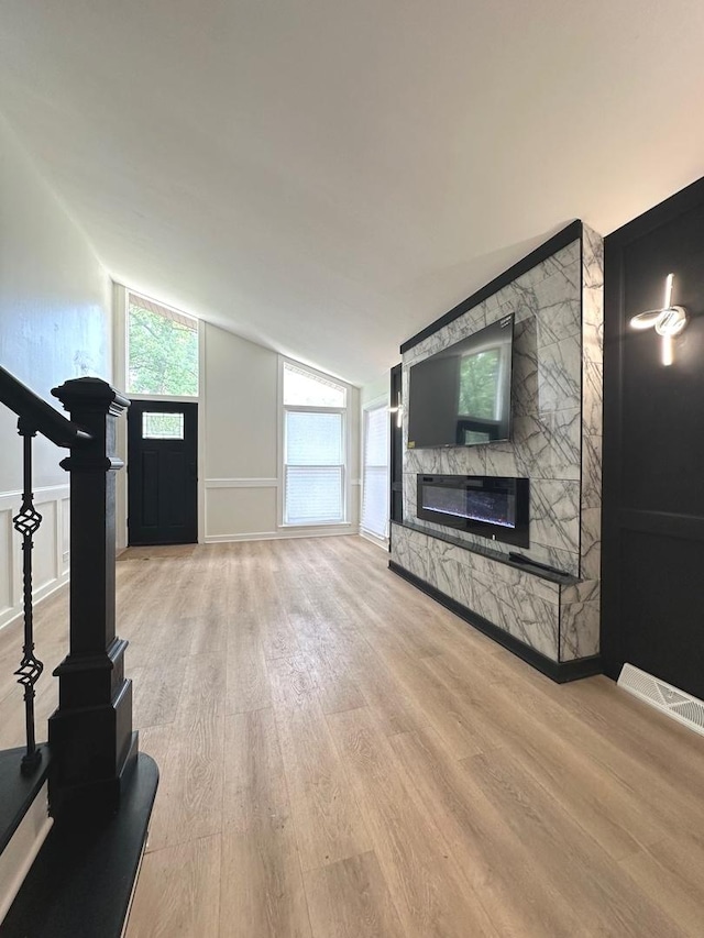 unfurnished living room featuring a fireplace, lofted ceiling, and light hardwood / wood-style flooring