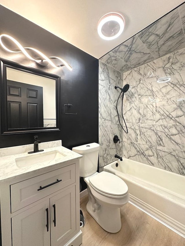 full bathroom with hardwood / wood-style flooring, tiled shower / bath combo, vanity, and toilet