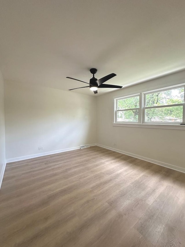 empty room with ceiling fan, wood-type flooring, and a healthy amount of sunlight