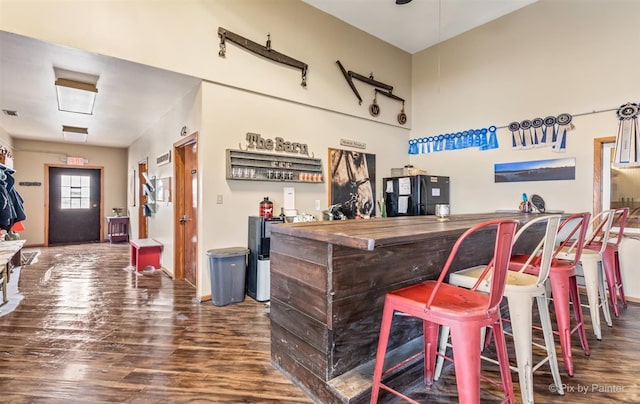 bar featuring black fridge and dark hardwood / wood-style flooring