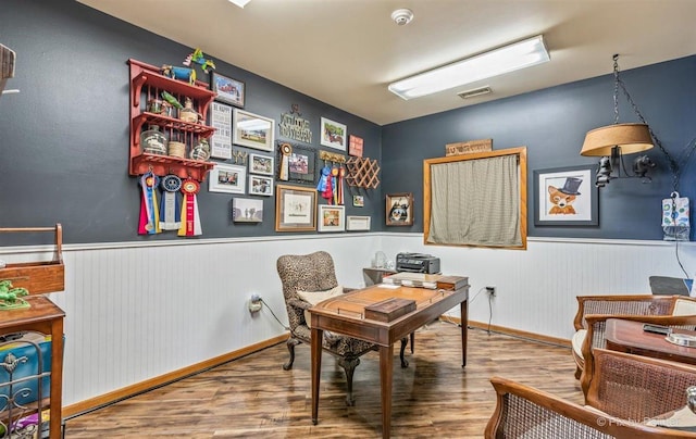 home office featuring a wainscoted wall, visible vents, and wood finished floors