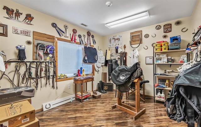 interior space featuring baseboards, visible vents, baseboard heating, and wood finished floors