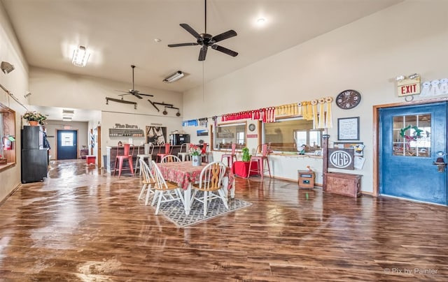 dining area with a high ceiling, ceiling fan, and wood-type flooring