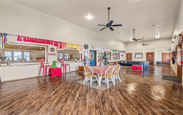 dining room featuring a towering ceiling, ceiling fan, and wood finished floors