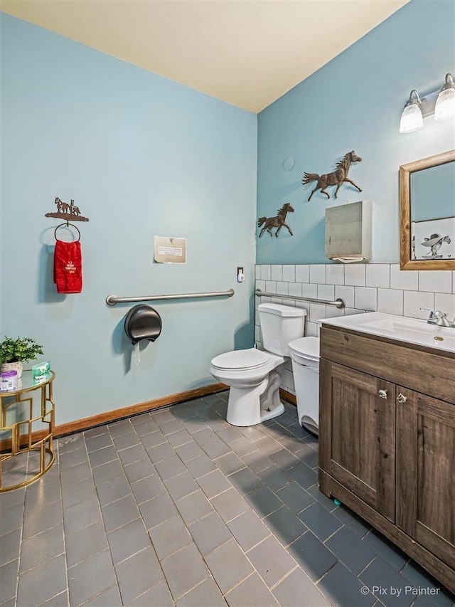 bathroom featuring toilet, tile patterned flooring, tile walls, and vanity