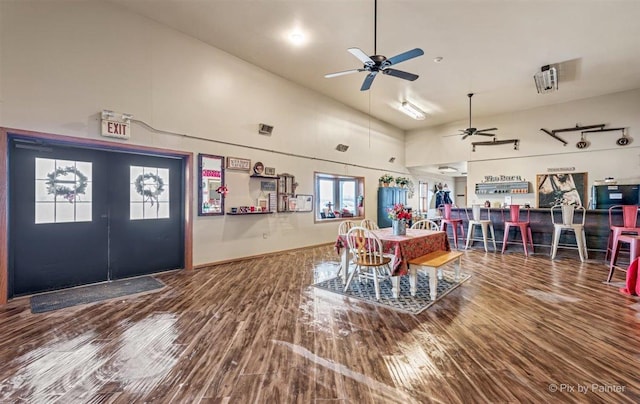 dining space with ceiling fan, a towering ceiling, and wood finished floors