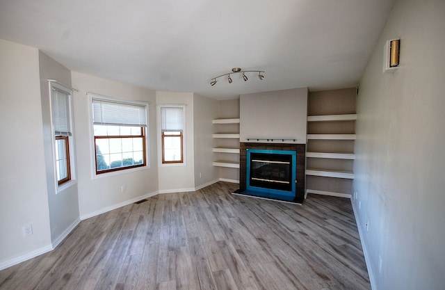 unfurnished living room with hardwood / wood-style floors and rail lighting