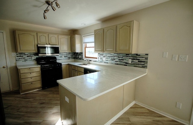 kitchen with light countertops, a sink, a peninsula, and black appliances