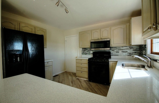 kitchen with wood finished floors, a sink, light countertops, black appliances, and backsplash