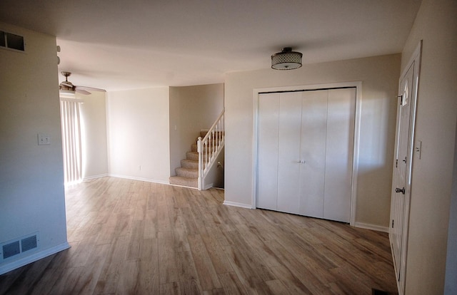 interior space with wood finished floors, visible vents, baseboards, and stairs