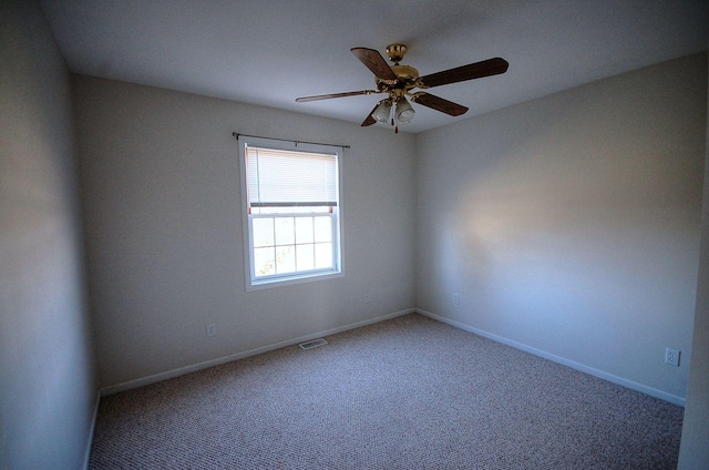 empty room with carpet floors, baseboards, visible vents, and ceiling fan