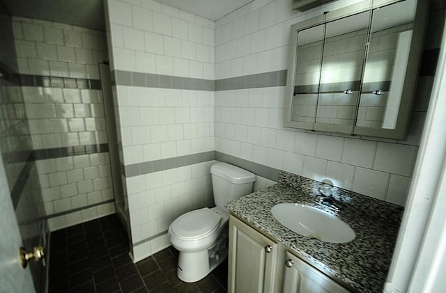 bathroom featuring tile patterned flooring, toilet, vanity, tile walls, and backsplash