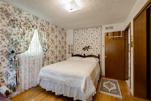 bedroom with light hardwood / wood-style floors and a textured ceiling