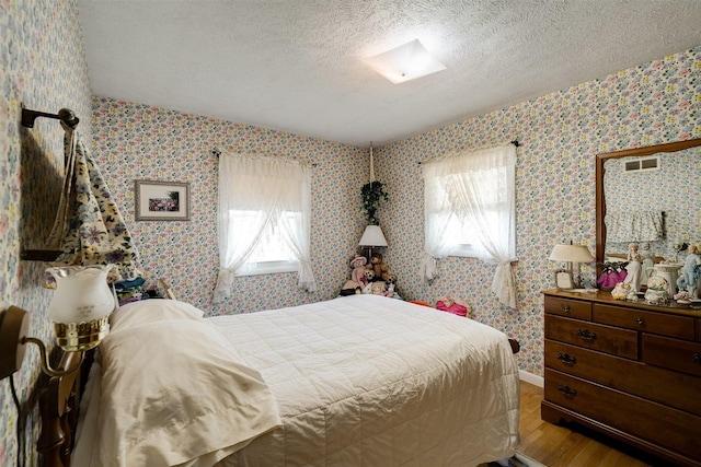 bedroom featuring multiple windows, hardwood / wood-style floors, and a textured ceiling