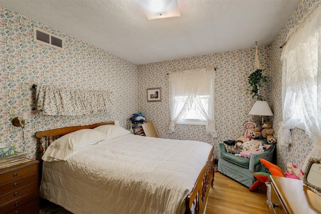 bedroom featuring light hardwood / wood-style floors and a textured ceiling