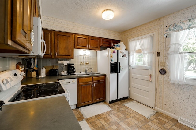 kitchen featuring tasteful backsplash, sink, white appliances, and a textured ceiling