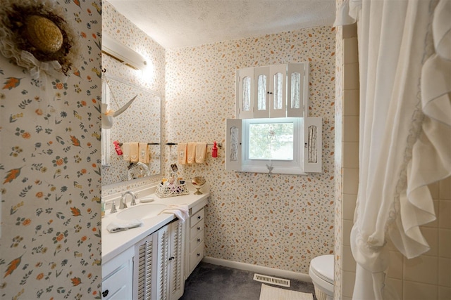 bathroom with vanity, toilet, and a textured ceiling