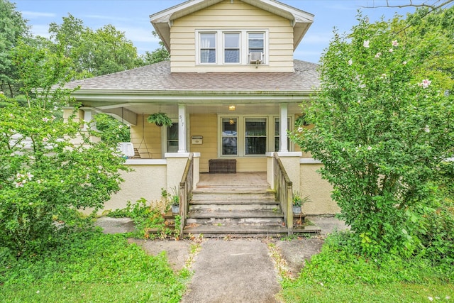 bungalow-style house with a porch and central AC unit